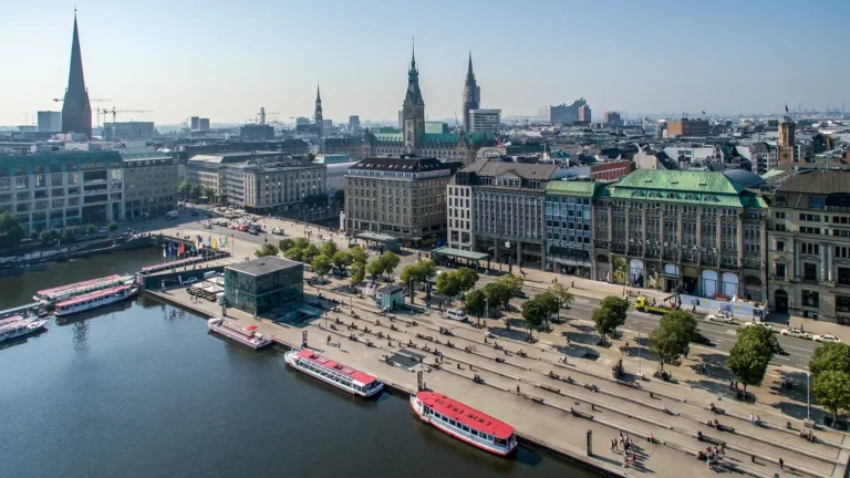 Eine Luftbildaufnahme vom Jungfernstieg in Hamburg. Zudem sieht man die Binnenalster und Alsterdampfer. Im Hintergrund die Skyline von Hamburg.