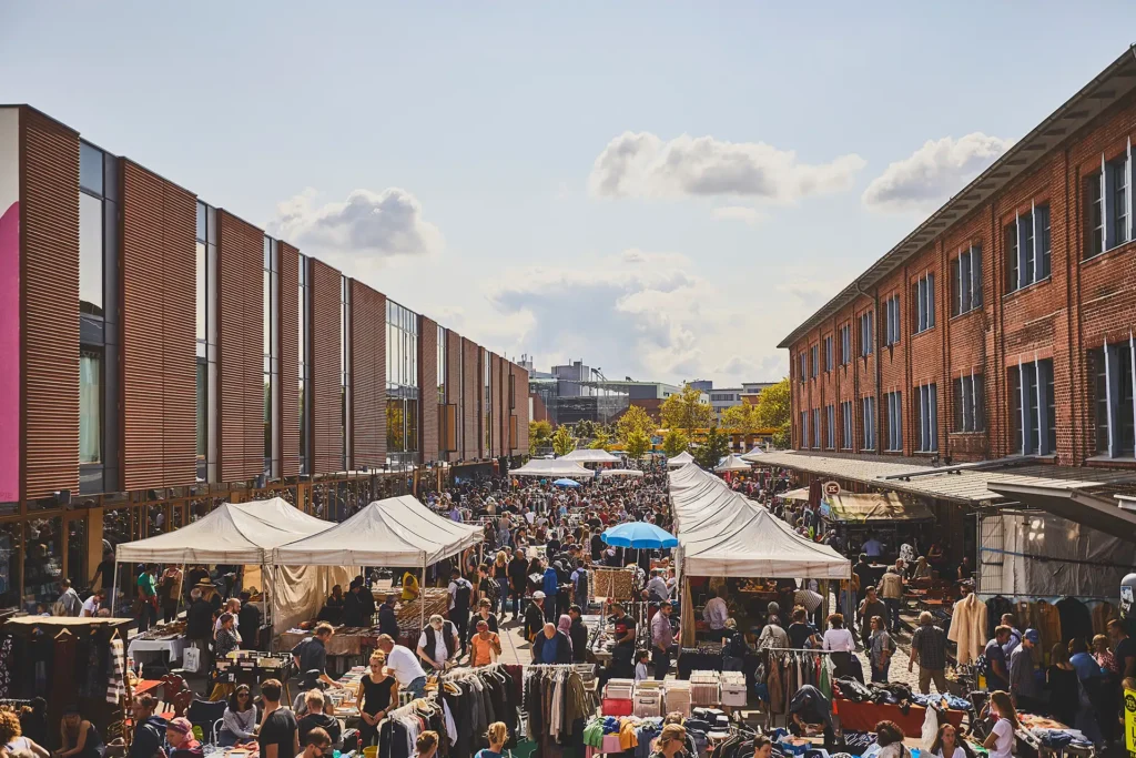 Zahlreiche Besucher zwischen zwei Gebäuden, die den Flohmarkt "Flohschanze" im Hamburger Schanzenviertel besuchen.
