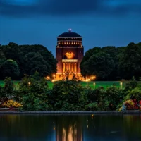Das Planetarium Hamburg bei Nacht. Im Vordergrund ist der Stadtparksee zu sehen.
