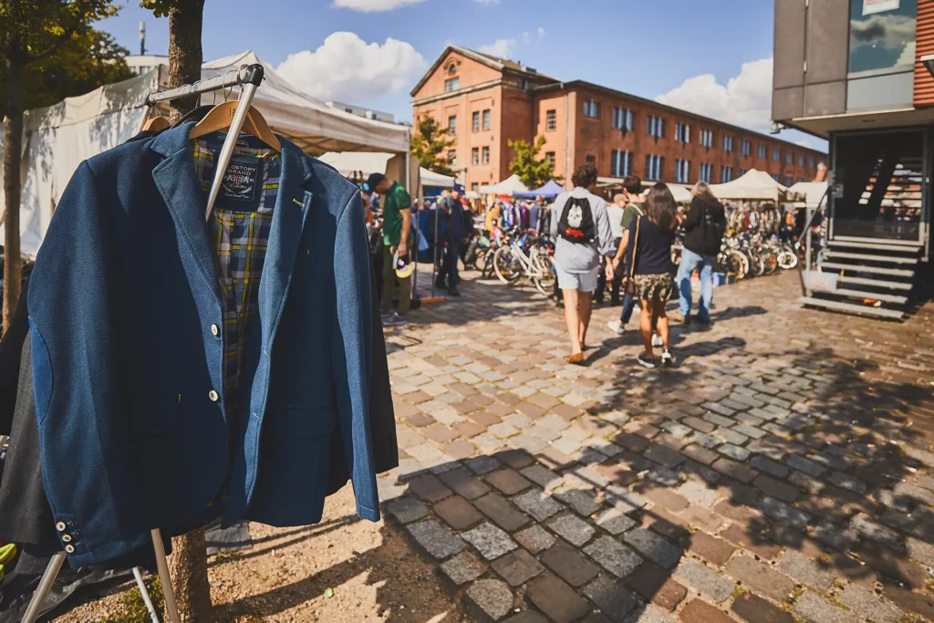 Der Flohmarkt "Flohschanze" im Hamburger Schanzeviertel. Im Vordergrund ist ein Jacket auf einem Kleiderbügel zu sehen. Im Hintergrund Besucher des Flohmarktes.